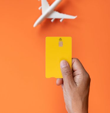 Summer vacation ticket purchase concept with commercial airplane in the background with orange color and credit card in one hand