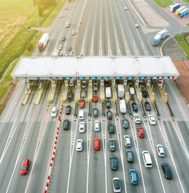 An overhead view of a busy toll road with many cars queuing up to pay the highway toll