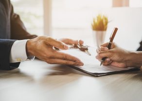 close up shots hands of client signing car lease form.