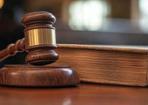 A wooden gavel rests beside a closed law book, symbolizing justice and legal proceedings.